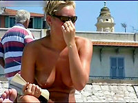 Short haired female in bikini is examining her bare tits on the beach!